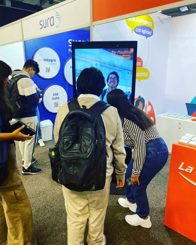 Estudiantes usando una pantalla interactiva en el stand de una feria